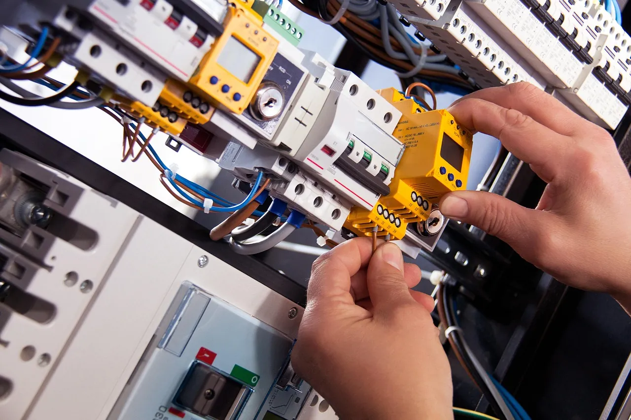 Electrician fitting protection devices on a DIN rail switchboard