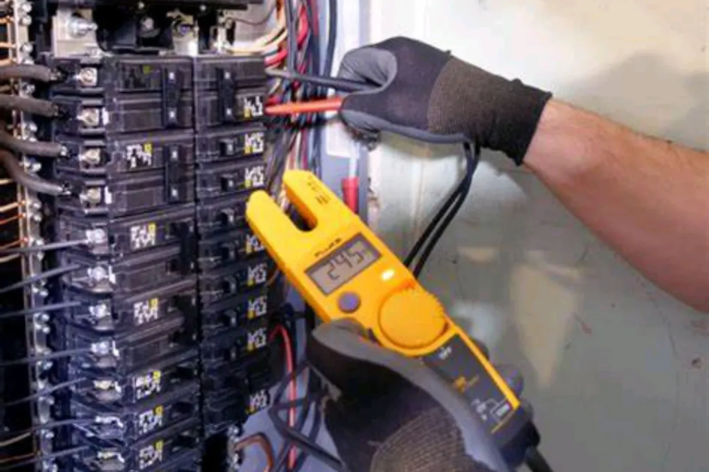 Electrician testing circuit breakers with a clamp tester